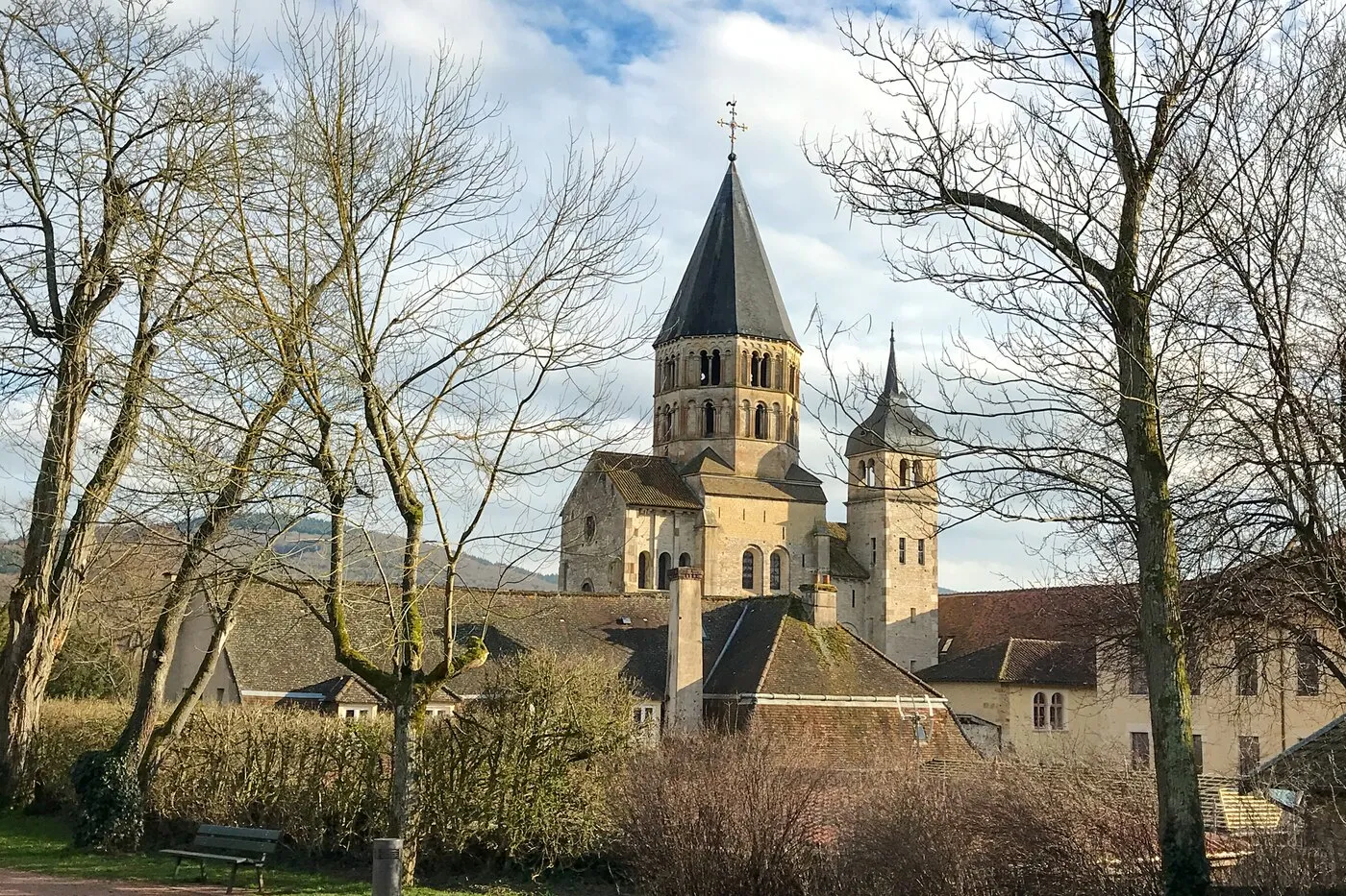 L’abbaye de Cluny et ses clochers au-dessus des arbres, sous un ciel de nuages