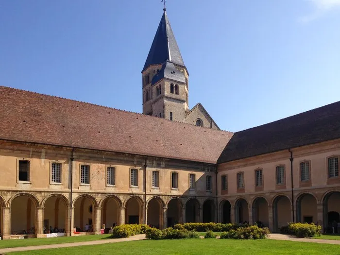 The cloister of Cluny Abbey and its bell tower, under a blue sky