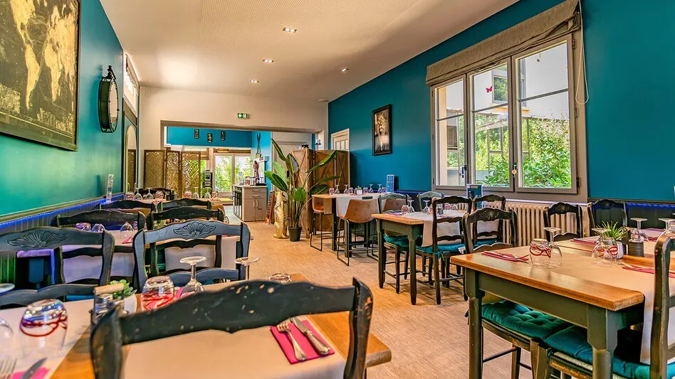La salle du Restaurant de l’Abbaye, ses murs bleu-vert et ses tables en bois dressées
