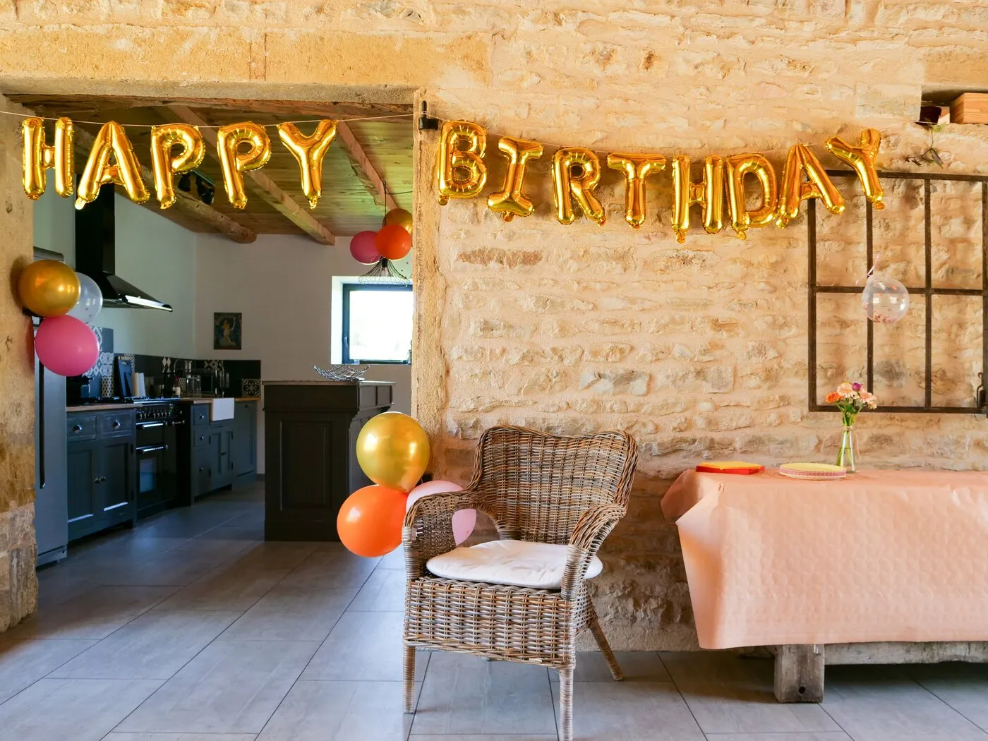 A Happy Birthday balloon garland in the kitchen, open to the dining room
