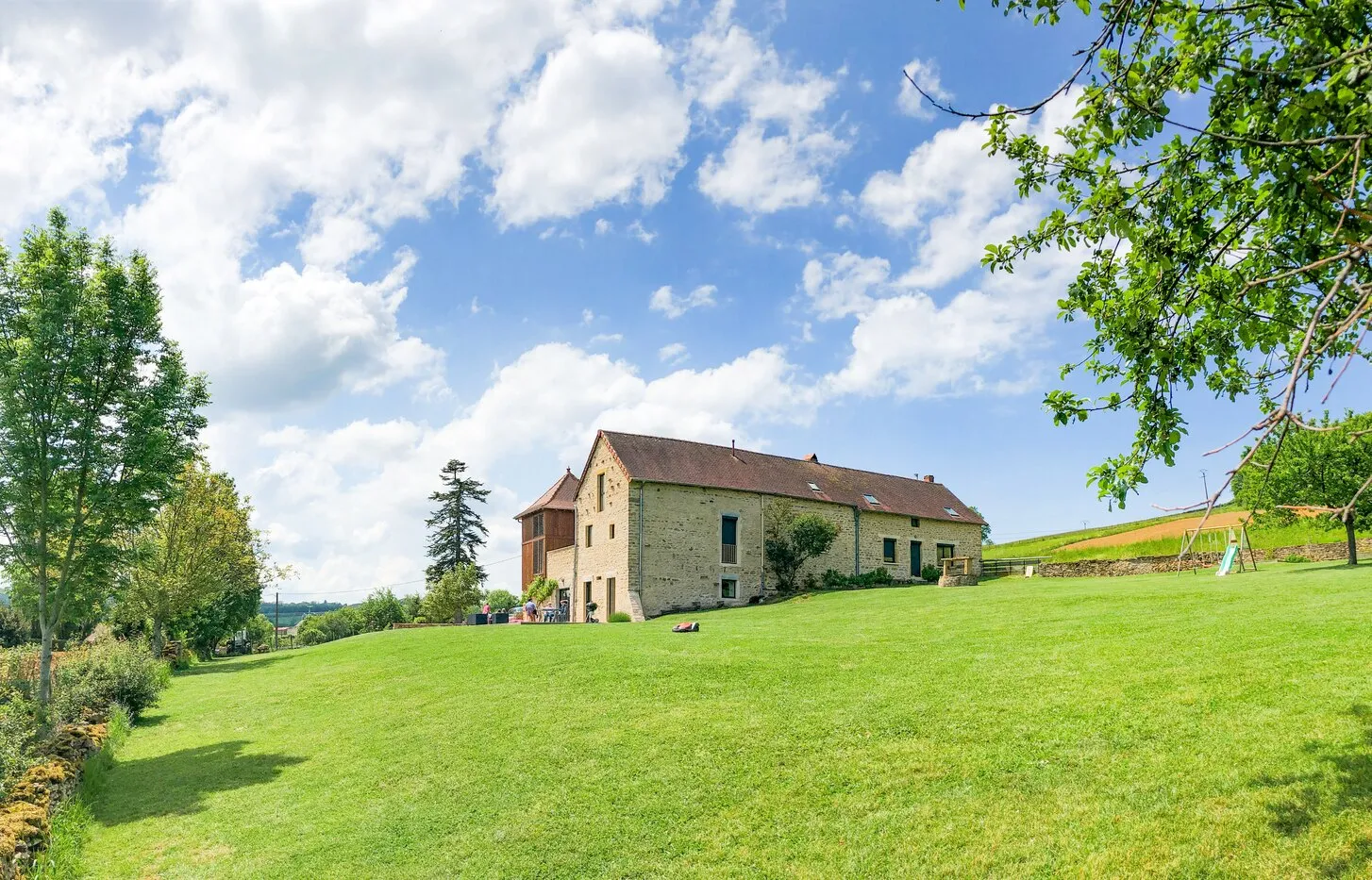 The house at the far end of the lawn, beneath a cloudy sky