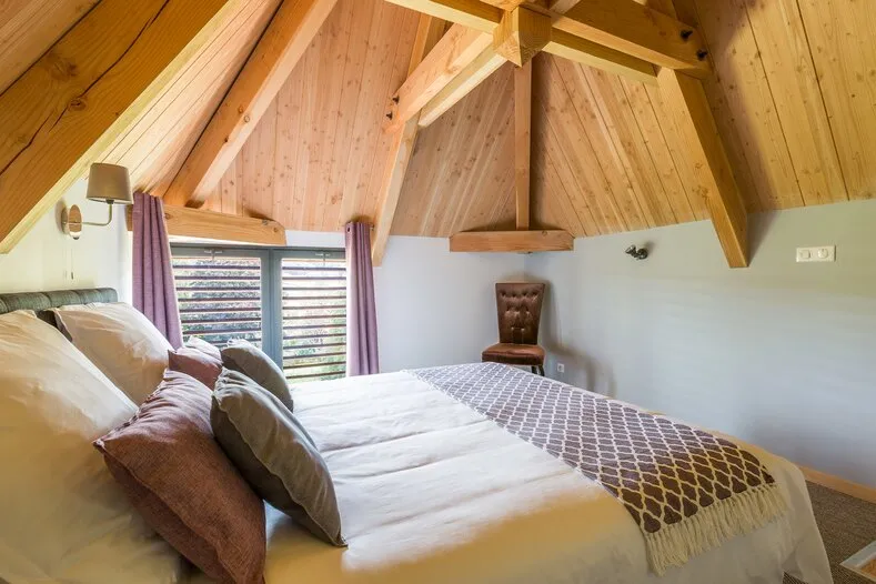 La chambre du Pigeonnier vue de côté, avec un fauteuil sous la charpente