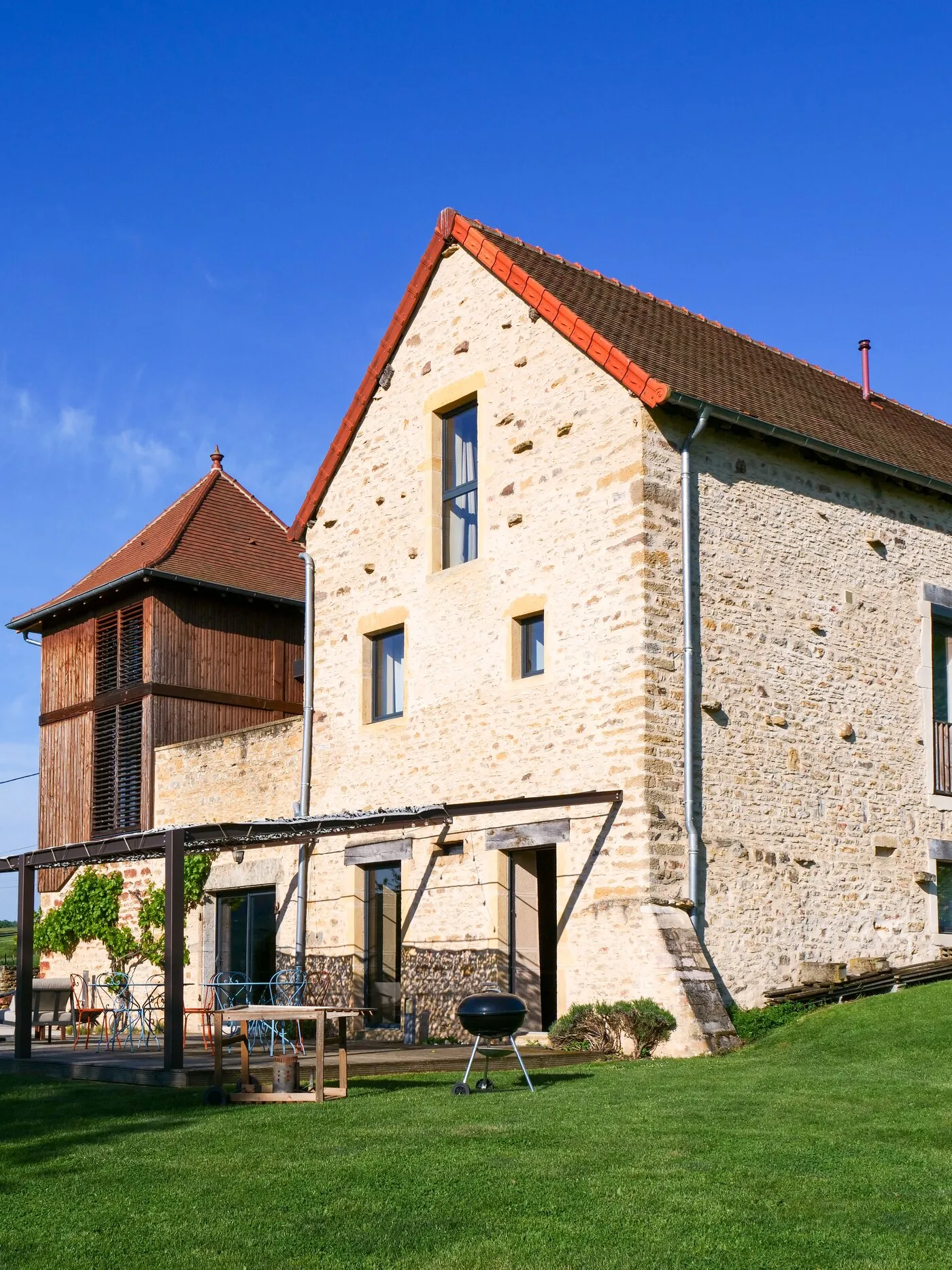 The golden-stone gable and the dovecote, the terrace under its pergola and the barbecue on the lawn