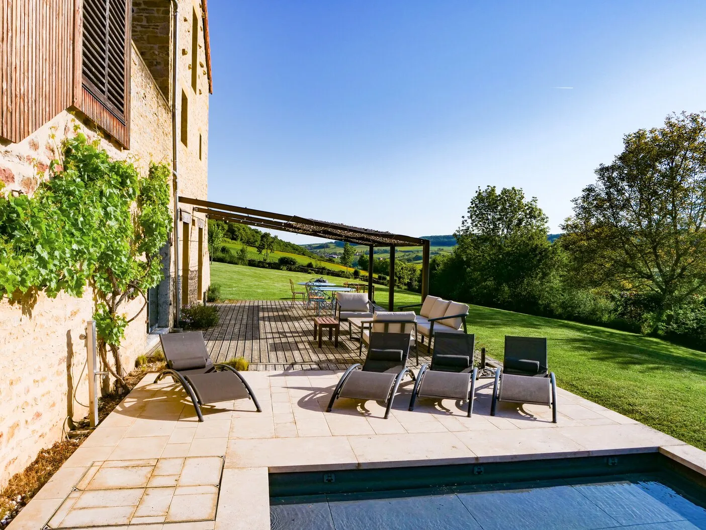 The terrace with its sun loungers, a vine climbing the wall