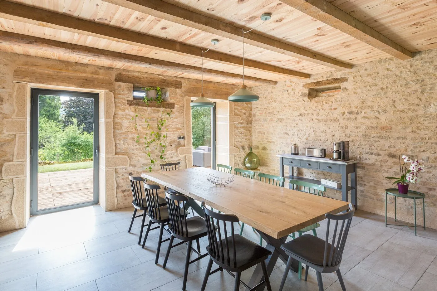 La salle à manger, grande table en bois et baies sur le jardin