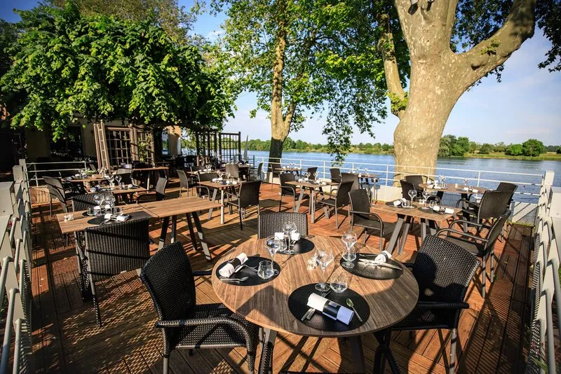 La terrasse du Poisson d’Or sous les platanes, au bord de l’eau