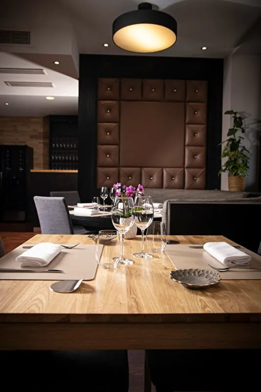 Une table en bois dressée dans la salle du Saint Amour, devant un mur capitonné