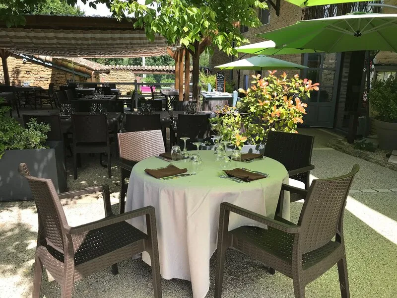 La terrasse de L’Embellie, une table ronde dressée sous les parasols verts